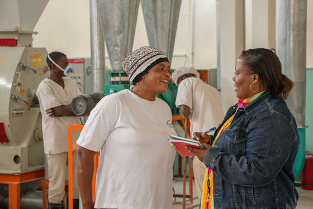 TechnoServe staff talk to employees of a food processing plant