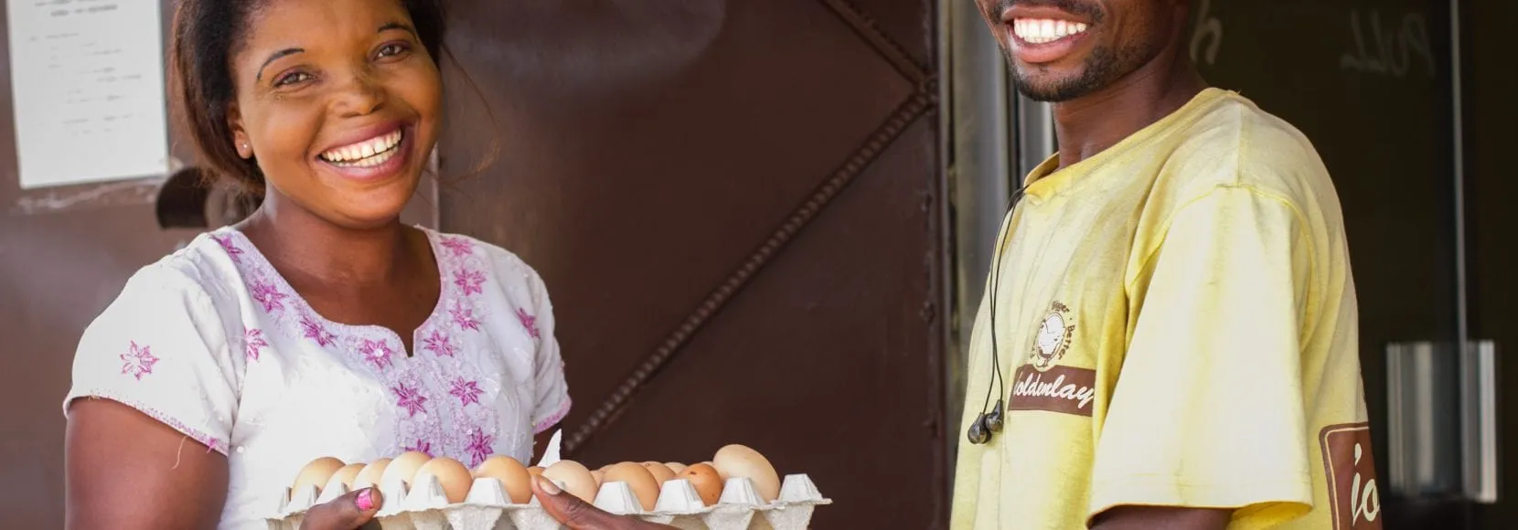 Two smiling people exchanging eggs