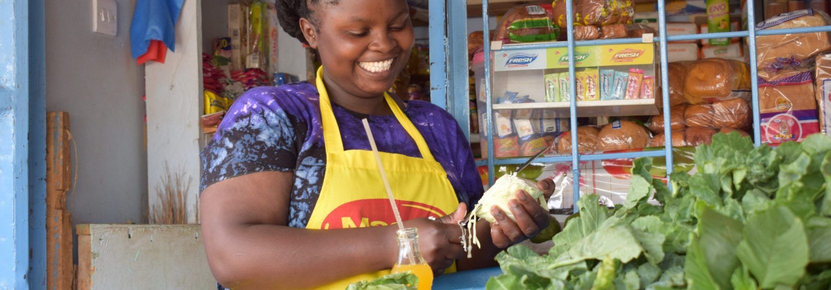 A woman stands in front of her small shop in Kenya