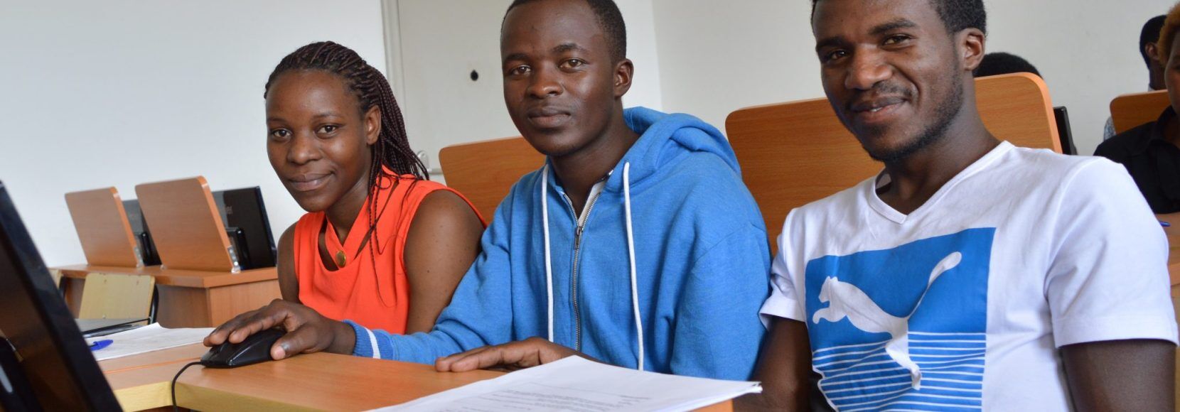 three young people in Africa doing job training with a computer