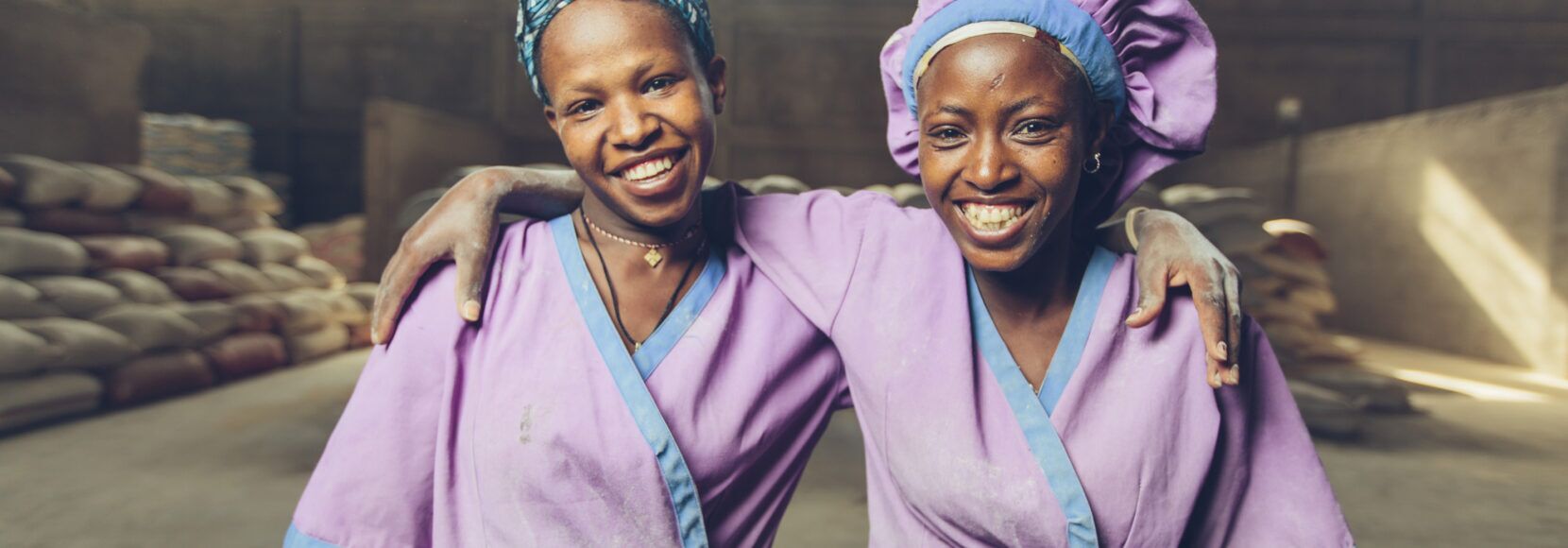 Two women smiling and working at a grain mill in Sannie, Ethiopia. Part of a food fortification quiz.