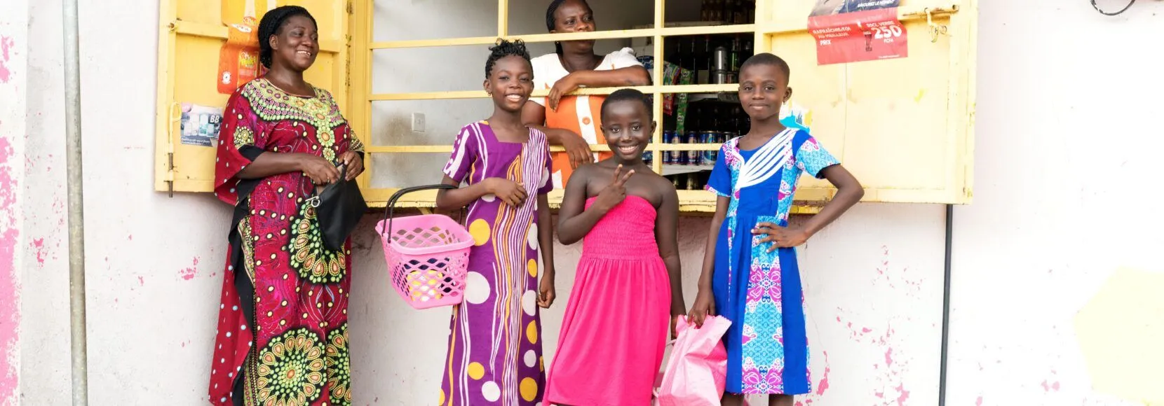 Women and children smile outside a micro-retail shop in Nigeria.