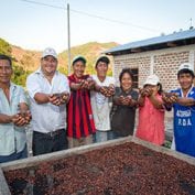 Group of people smiling holding up cocoa beans