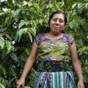 Woman smiling in front of coffee trees in Guatemala