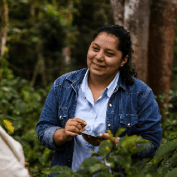 Woman smiling while working around coffee trees