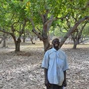 Person smiling surrounded by trees