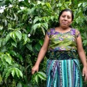 Woman smiling surrounded by coffee trees