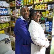 Smiling couple standing in their grocery store