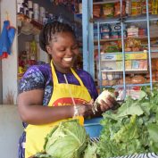 A woman stands in front of her small shop in Kenya