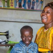 Human-centered design can power incredible solutions for international development. A woman holds a mobile phone near a sewing machine -