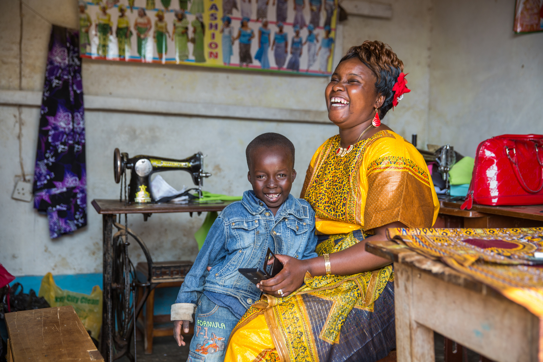 A woman holds a mobile phone near a sewing machine