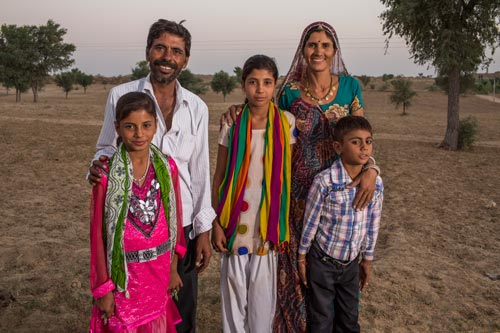 Family standing in a field and smiling.