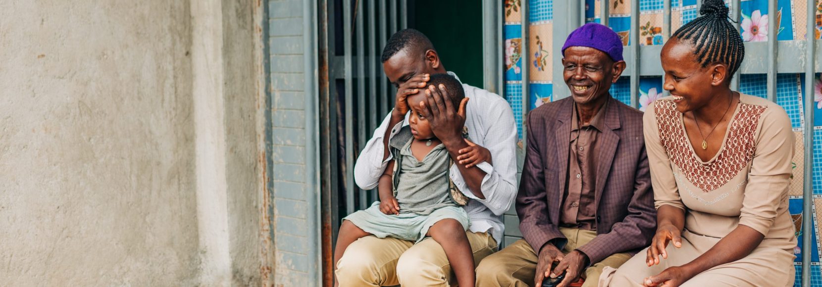 Coffee farmers in the Michiti cooperative with their child in front of a house.