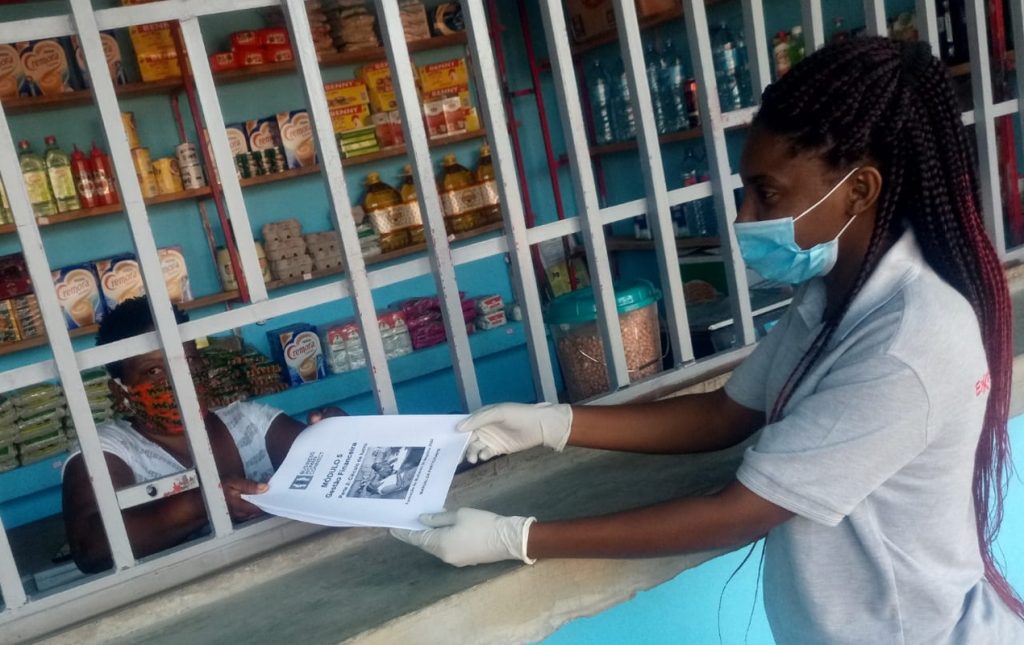 A TechnoServe business advisor provides entrepreneurship training material to a food vendor in Mozambique during the pandemic.