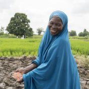 A farmer in Nigeria carries a handful of seeds on her plot of land.