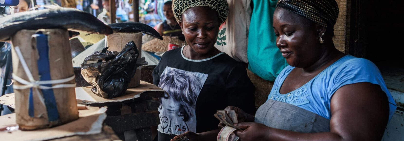 A woman selling fresh fish collects money from a client at a market in the Obalende area of Lagos