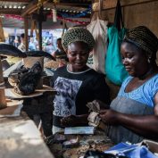 A woman selling fresh fish collects money from a client at a market in the Obalende area of Lagos