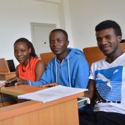 three young people in Africa doing job training with a computer