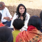 TechnoServe's new Board member Divy Kumar listens with an expression of positive interest as a group of dark-haired women wearing saris face her. The woman on the far right is explaining how the group is using new regenerative agricultural practices. TechnoServe works with farmers on sustainable livelihoods. This image was taken by TechnoServe staff on location in the Indian state of Maharashtra.