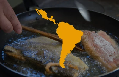A hand using chopsticks to fry fish in a pan, with an outline of Latin America superimposed on the image.