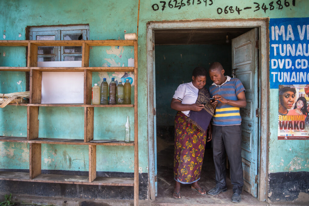 Two people standing in front of a shop in Kenya. Part of a blog post on AI in small business.