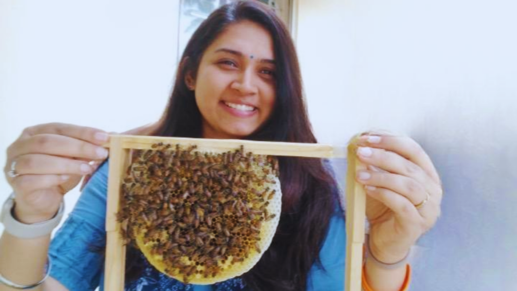 A woman holds a honeycomb covered in bees. Part of a blog post on women entrepreneurs in India.