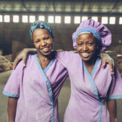 Two women smiling and working at a grain mill in Sannie, Ethiopia. Part of a food fortification quiz.