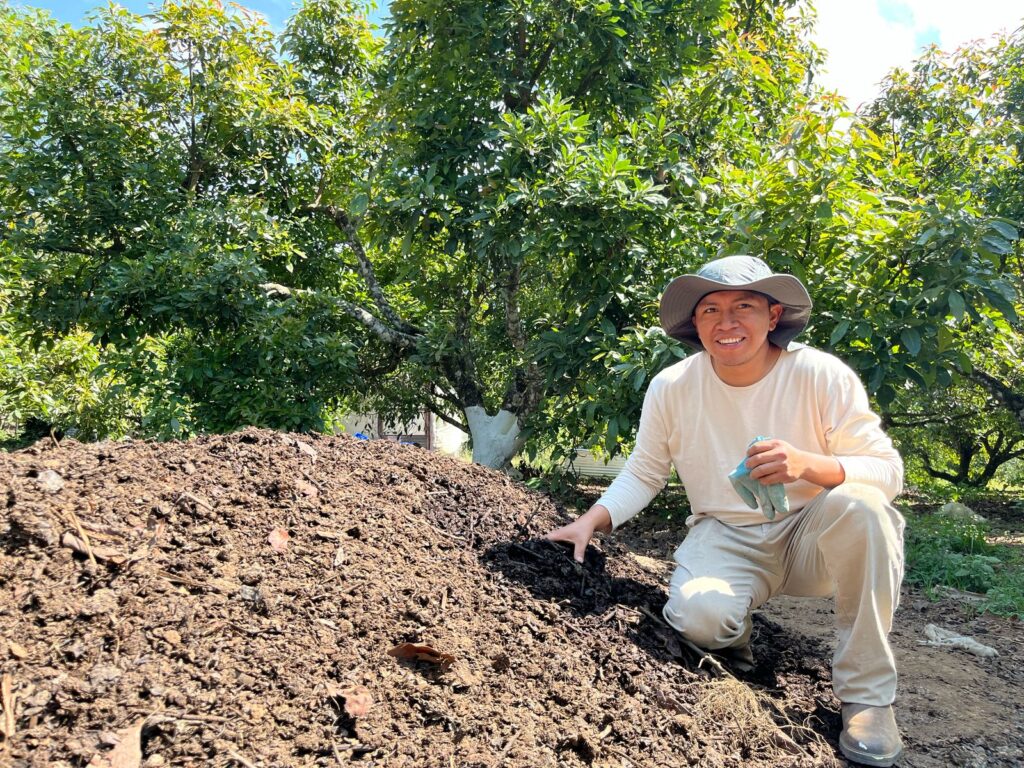 A man in Guatemala crouches with soil. Part of a blog post on regenerative agriculture.
