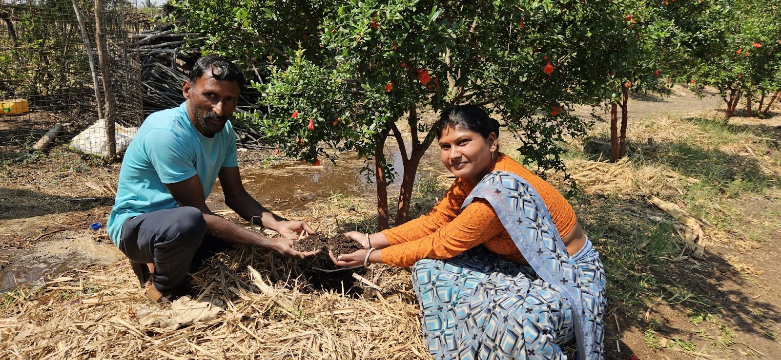 A man and a woman crouch in a field holding soil in India. Part of a blog post on regenerative agriculture.