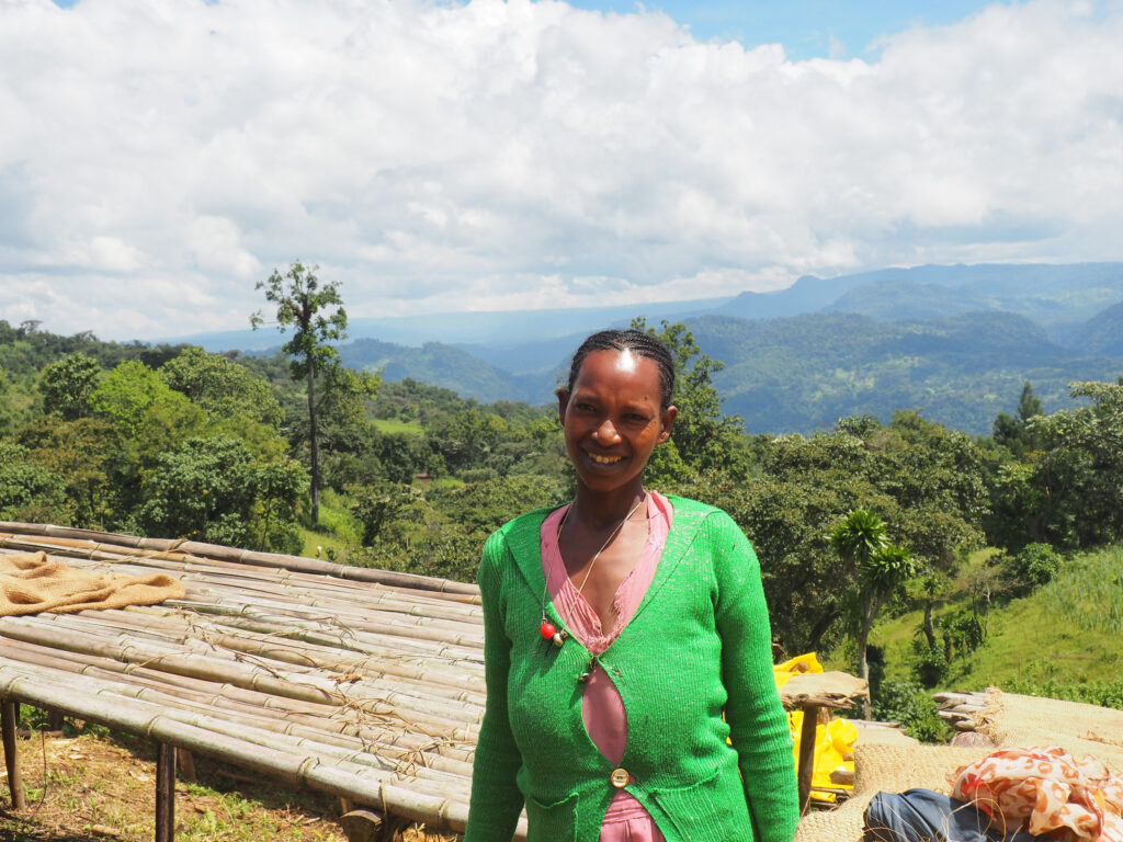 A woman stands near a coffee farm