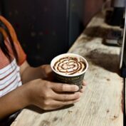 A woman pours a latte in a small coffee shop in Guatemala. (TechnoServe / Michelle Whiting) Part of a blog post for National Coffee Day 2025.
