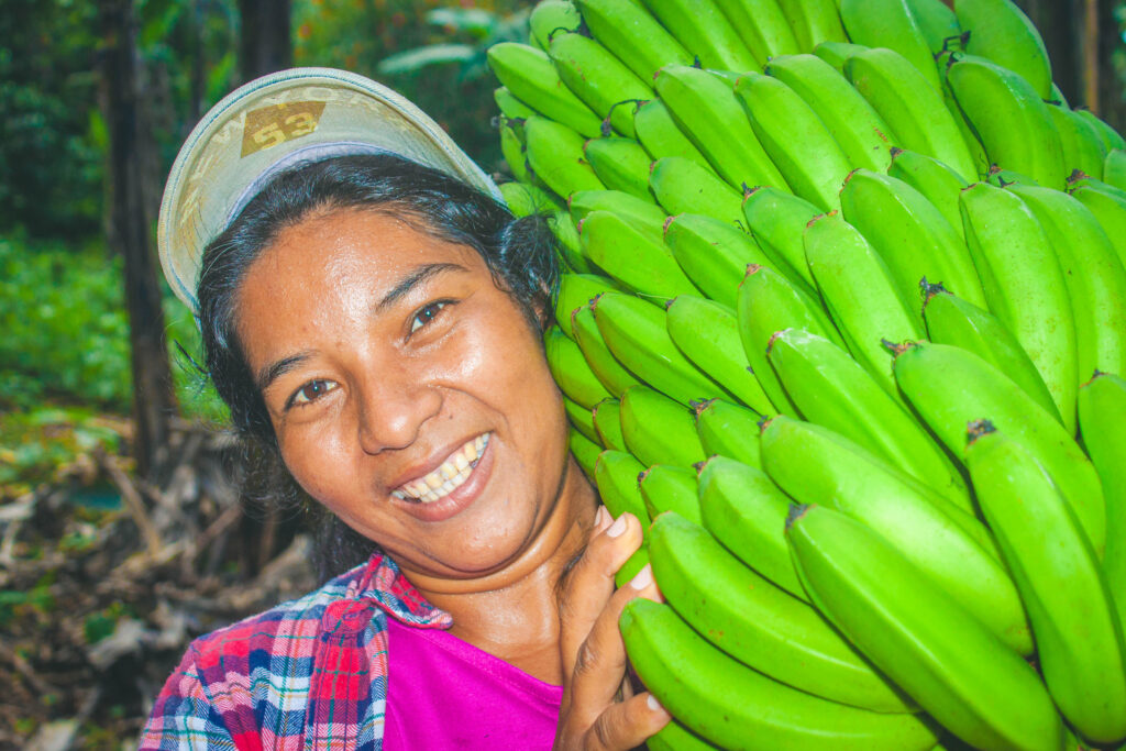 Woman smiling and holding green bananas